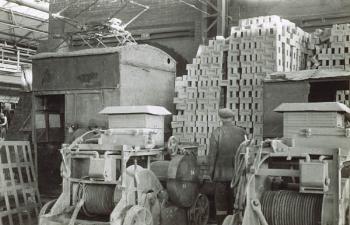 Interior of shed with stacks of bricks workman